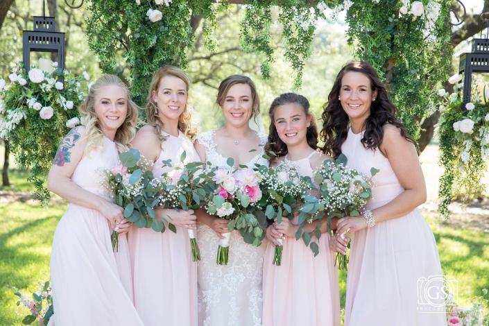 A stunning wedding party of bridesmaids in soft pink dresses with elegant floral bouquets. 